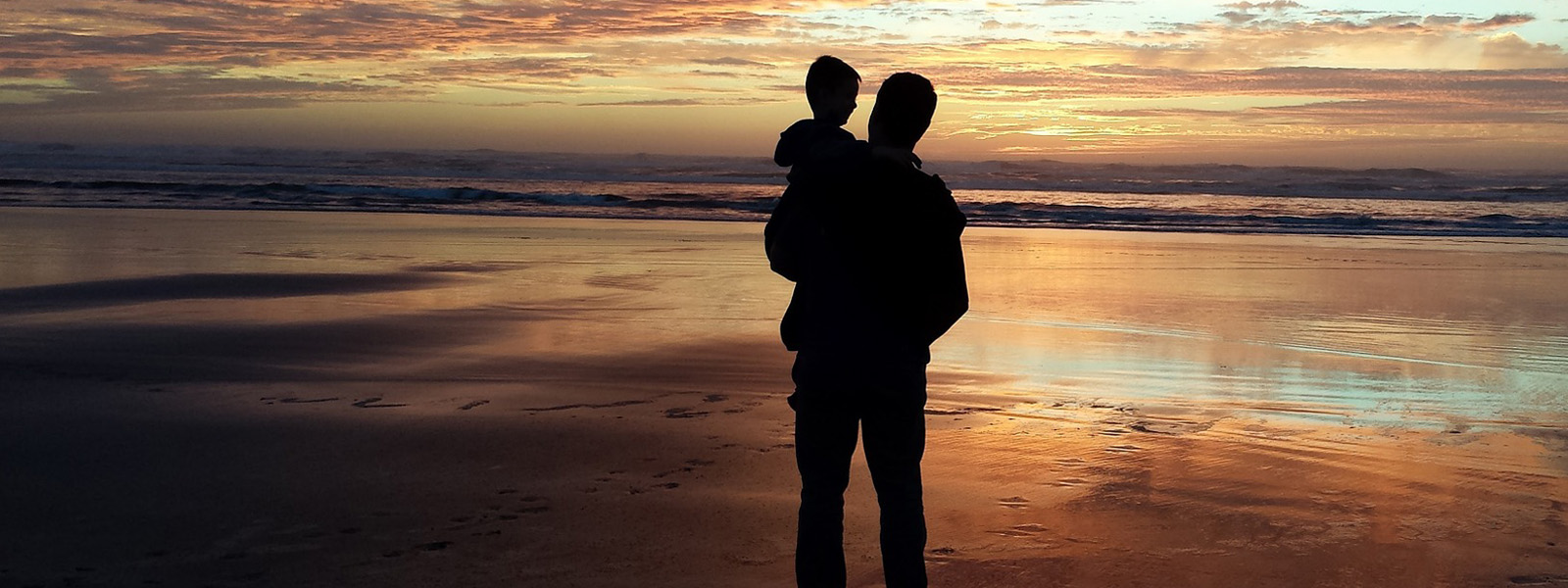A father and child on a beach at sunset