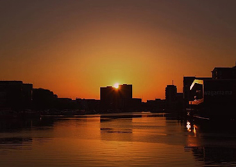 Picture of the Brayford at sunset, with the sun setting behind silhouettes of the cygnet wharf accommodation