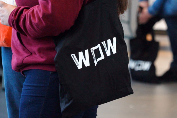 A student holding a black tote bag with WOW written on it