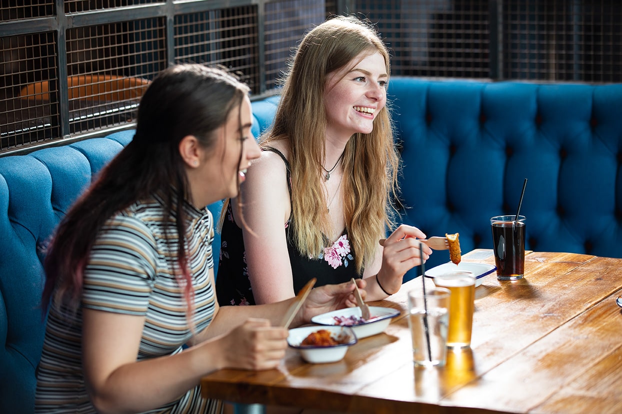 Two students sat in Towers with food and drinks