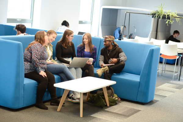 A group of students sitting around a laptop