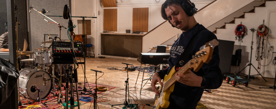 A student playing guitar on a trip to London's Abbey Road Studios