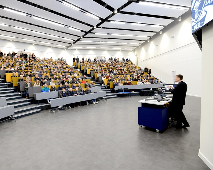 Man talking to people in a lecture theatre