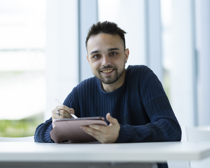 A student holding a tablet and a pen