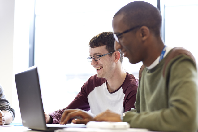 Men sitting at a desk with a laptop.