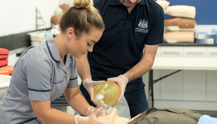 A student nurse working in a mock hospital setting