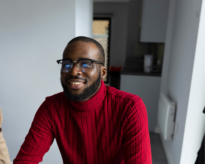 A male student in a red top sat smiling