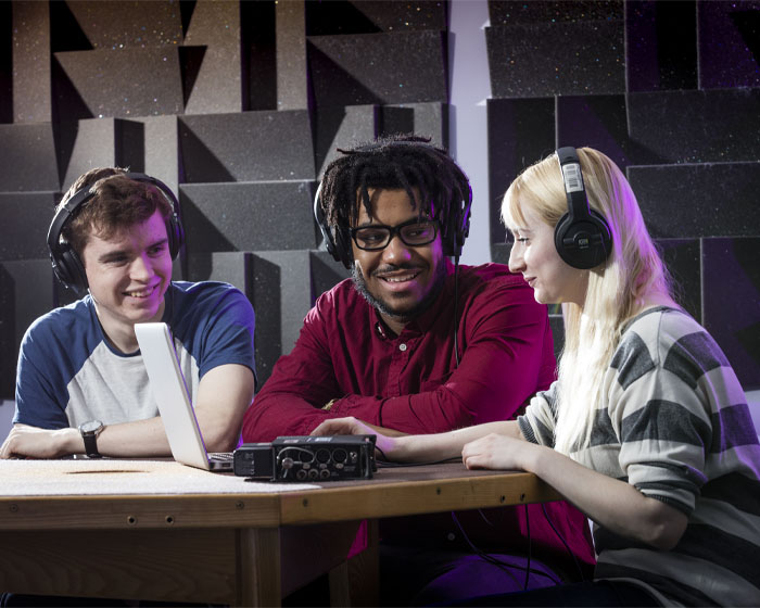 A group of students wearing headphones and working in a sound studio