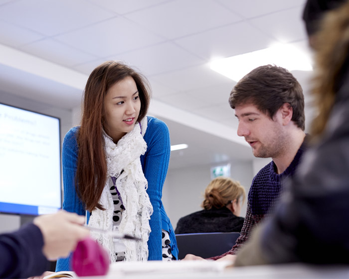 A lecturer talking with a student in a seminar room