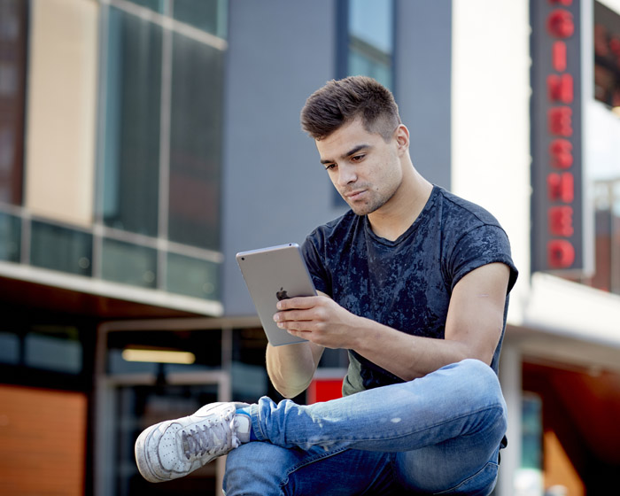 A student sat outside using a tablet