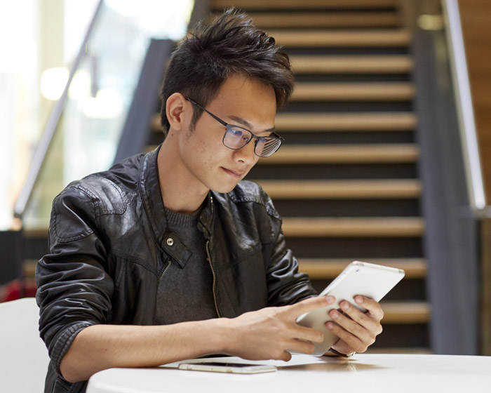 A student sat at a table working on a small tablet device