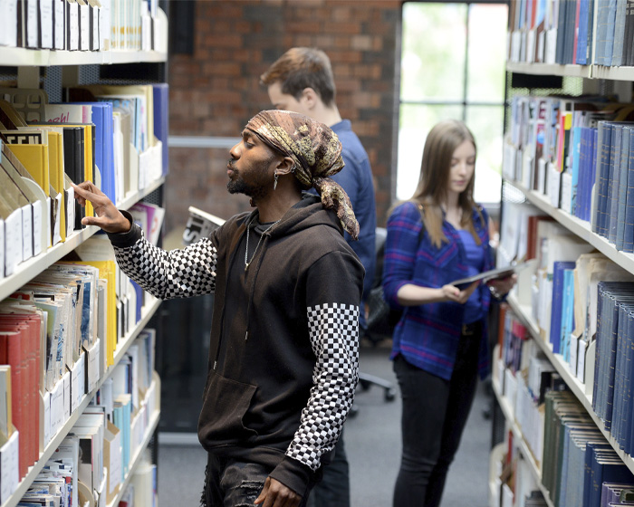 A group of students loooking at books in the library