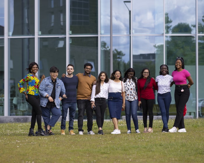 A group of student posing for a photograph outside the Isaac Newton Building