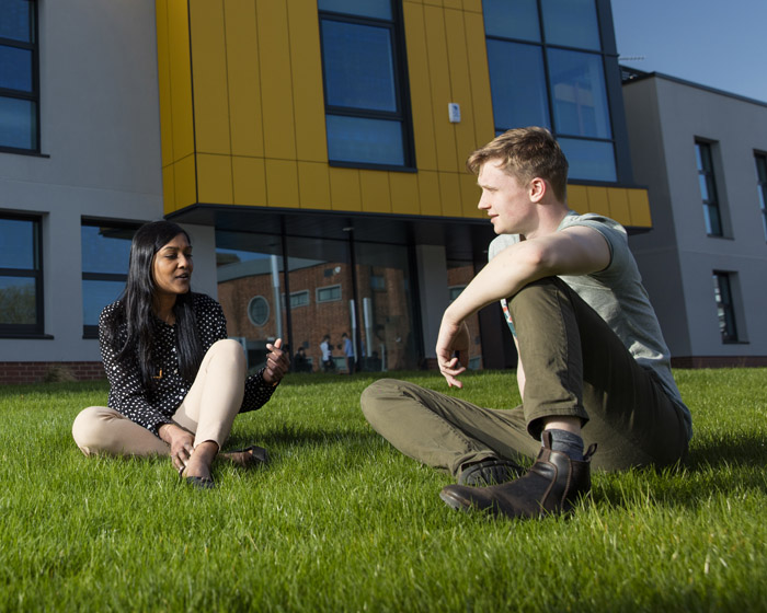 Two students sitting on the lawn and chatting