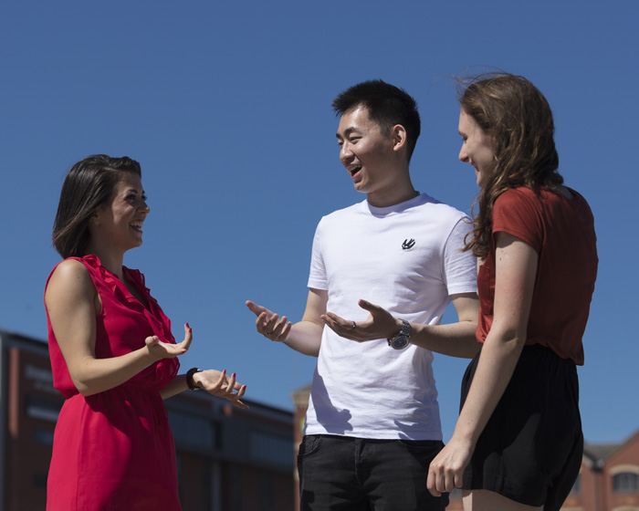 Three students stood chatting on campus
