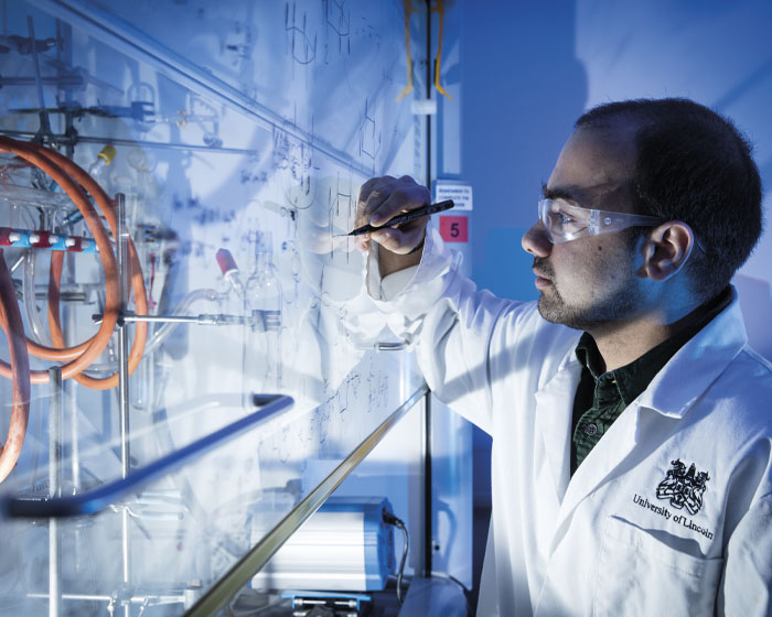 A student writing on a whiteboard in a science laboratory