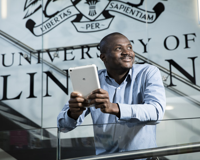 A student standing on a stairway holding a tablet device