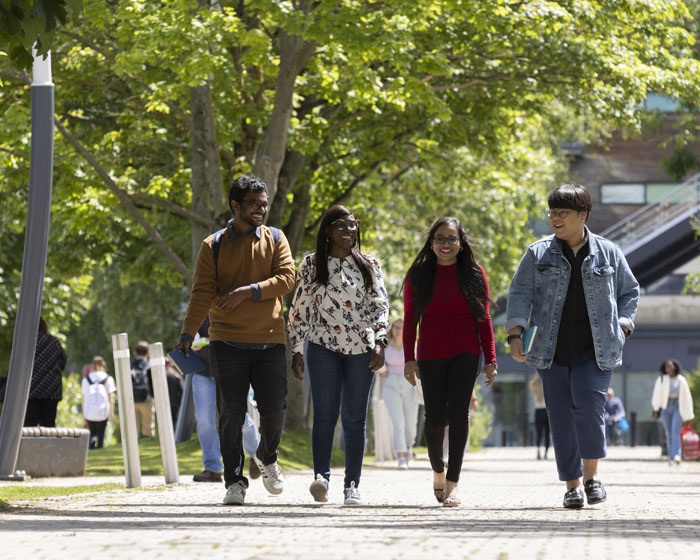 A group of students walking on campus in the sunshine