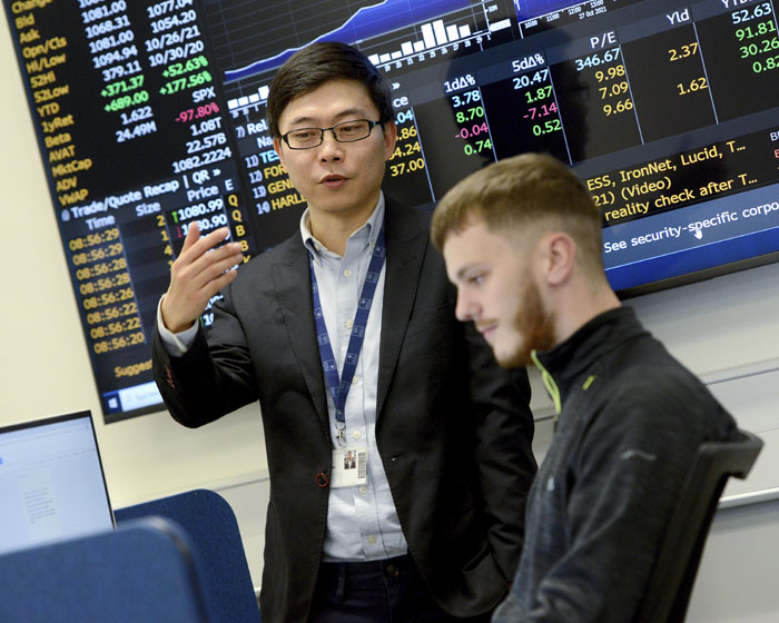 An academic talking to a student in the finance lab