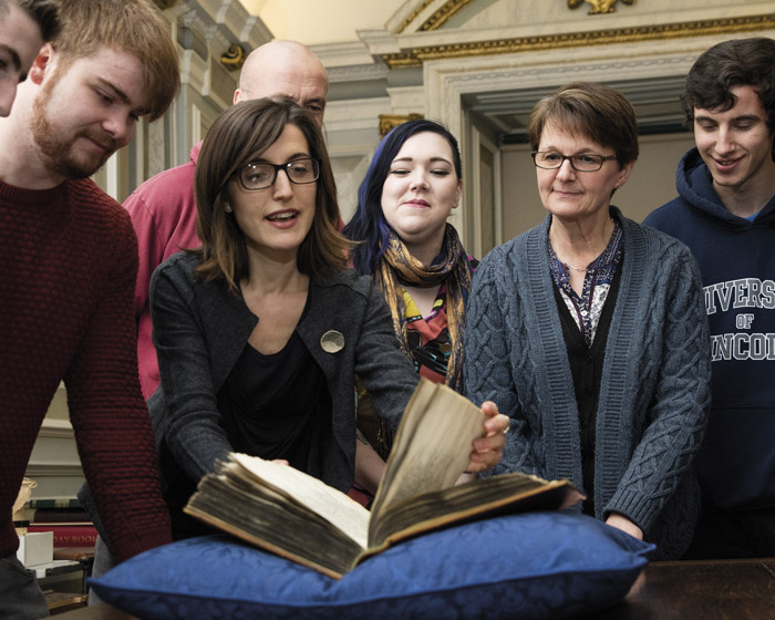 A lecturer talking to a group of students in an archives
