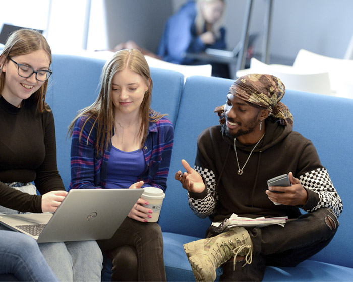 Three students sitting together and working on a laptop