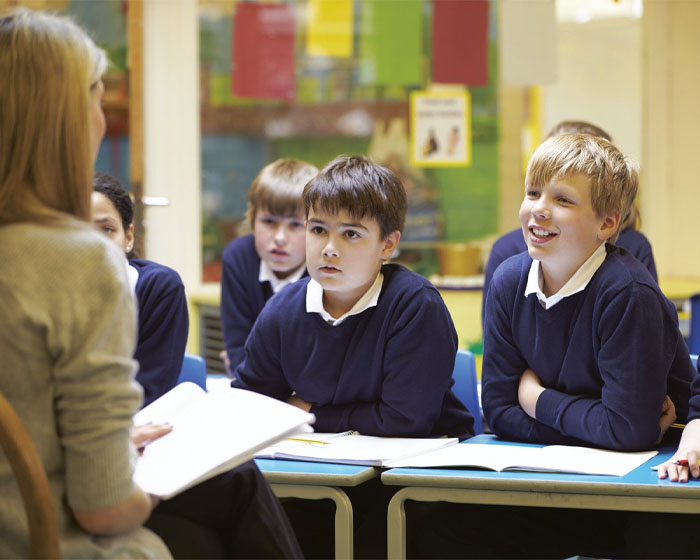 A teacher speaking to a group of pupils in a school classroom