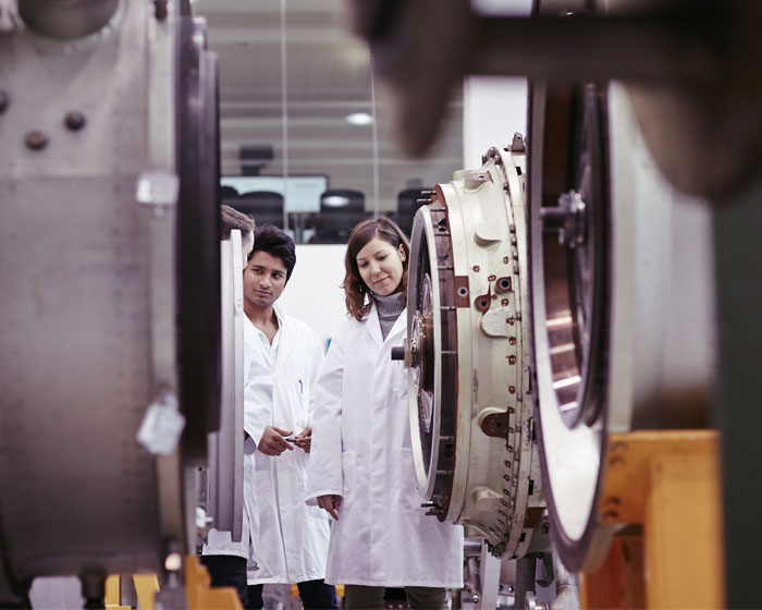 Two students examining large turbines