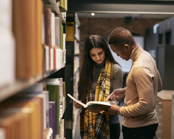 Two students reading a book in the library