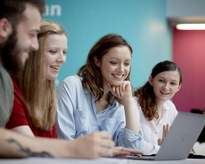 A group of students sat together working on a laptop