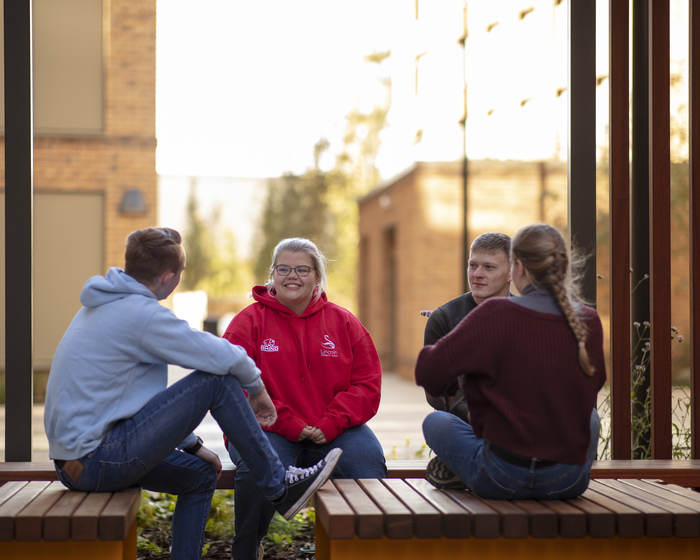 Students sitting outdoors in a communal area on campus.