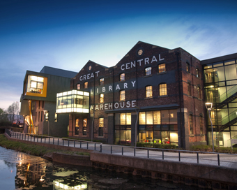 Exterior shot of the University Library lit-up at night, with the Sparkhouse enterprise building to the left