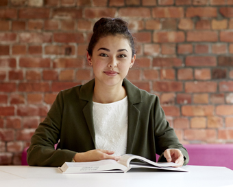 Female student sat at a table with an open textbook