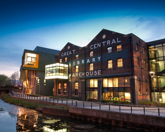 Exterior shot of the University Library lit-up at night, with the Sparkhouse enterprise building to the left