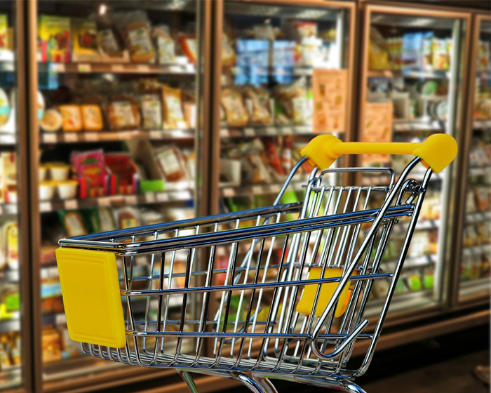 A shopping trolley in front of supermarket fridges