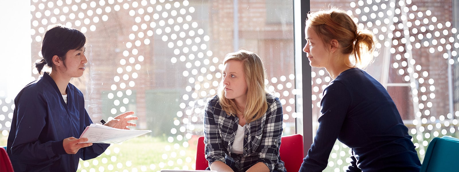 Three people sat talking at a table