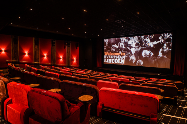 Rows of red sofas in front of a large cinema screen.