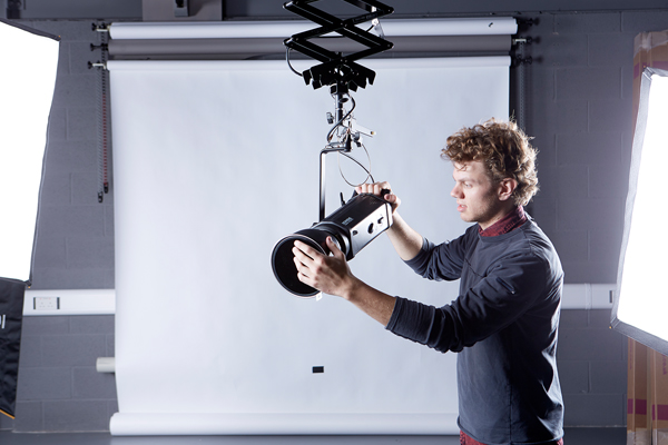 A student setting up a camera in a studio.