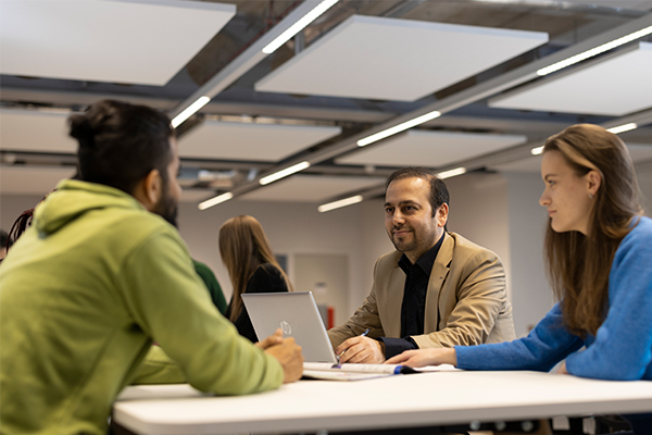 Students sat at a table with a lectuer