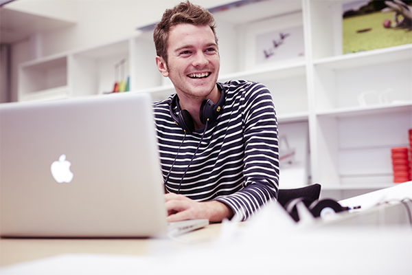 A male student sat with a laptop