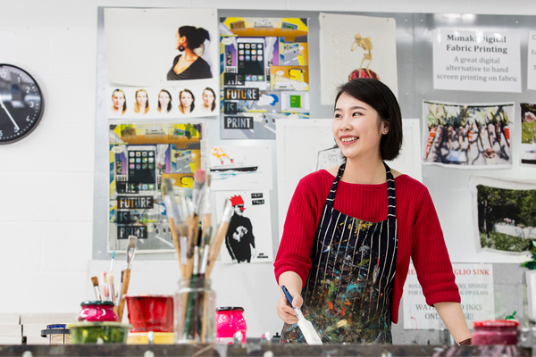 A woman stood in a workshop with a paintbrush