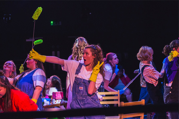 Students performing on stage with brushes