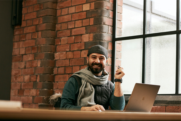 A student sat smiling in the library with a laptop