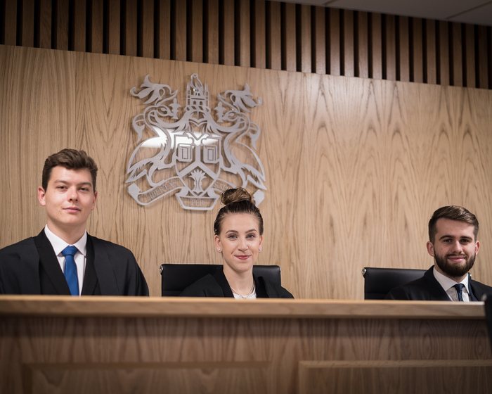 Law students sitting at a judge's bench.