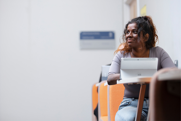 A student sat with an iPad smiling