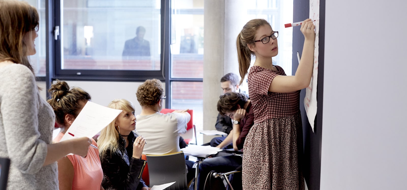 Female student writing on a whiteboard with a pen.