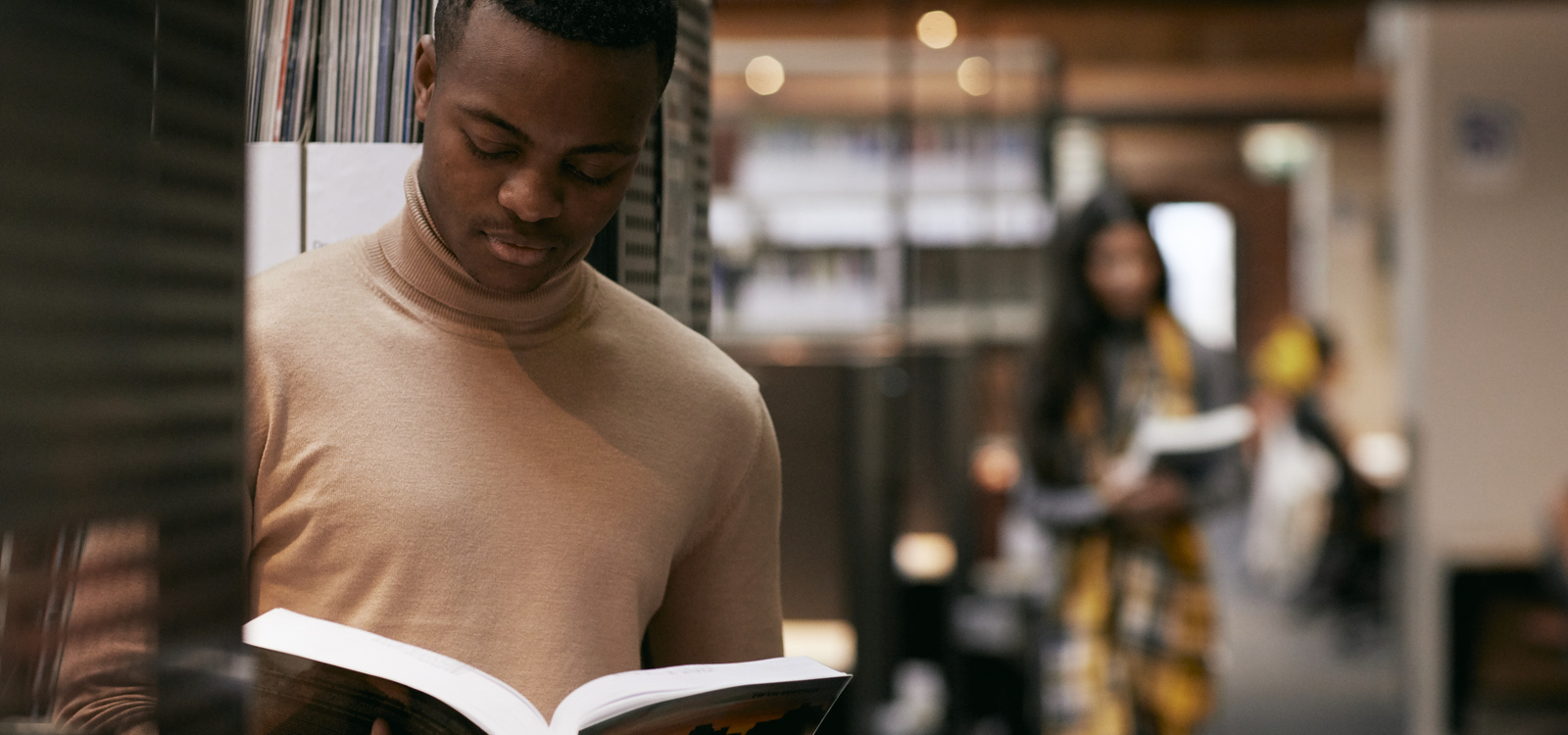 Male student reading a book in the library.