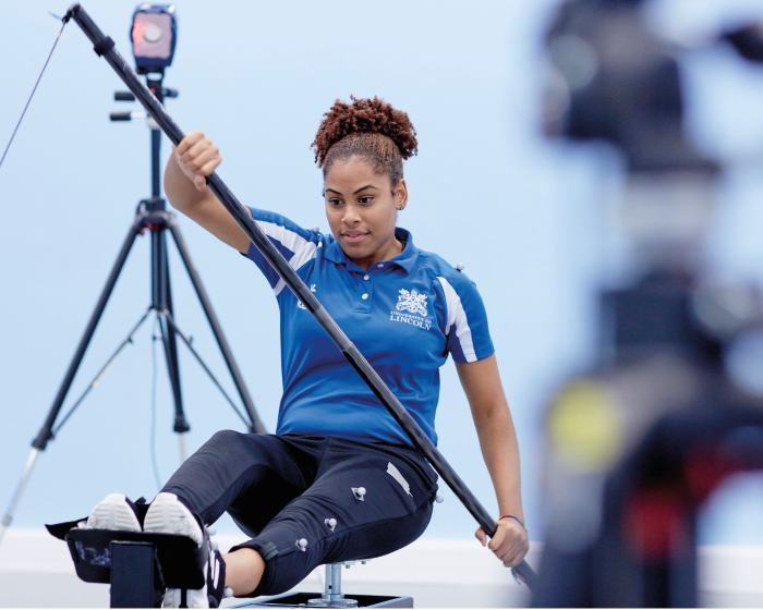 Sport Science student on an indoor rowing machine, with a set of paddles in her hands