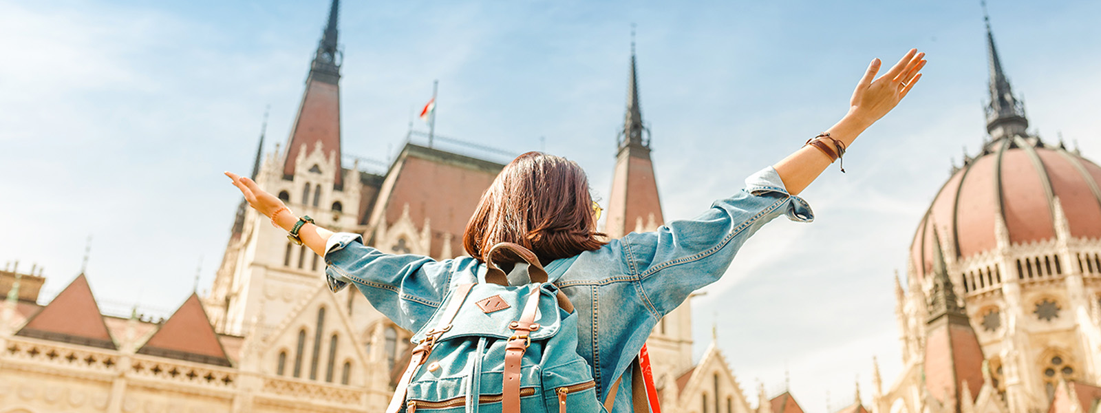 A student with their arms raised in front of a building