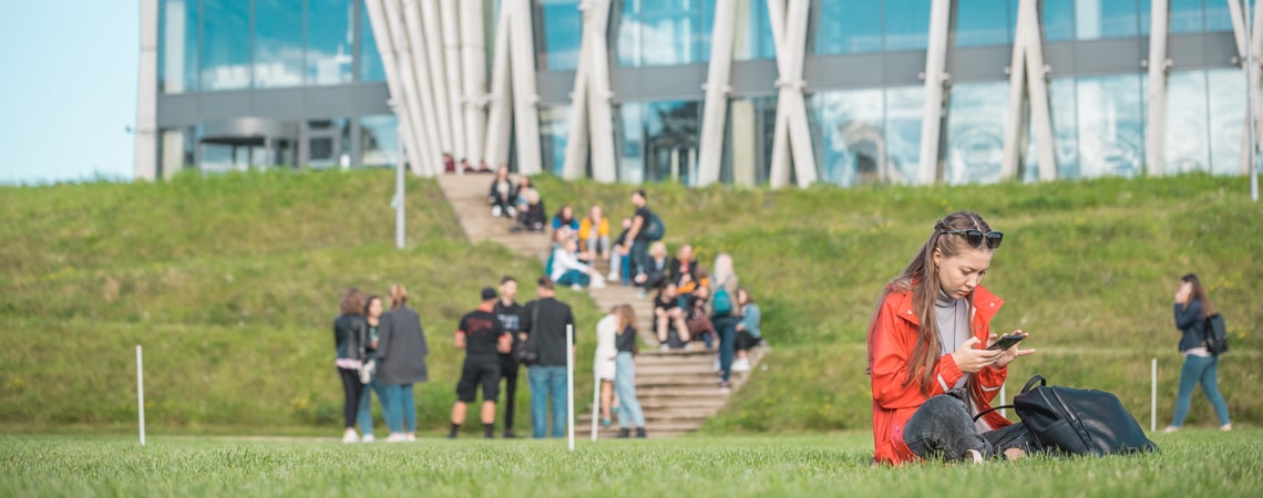 A student sitting on grass outside a building