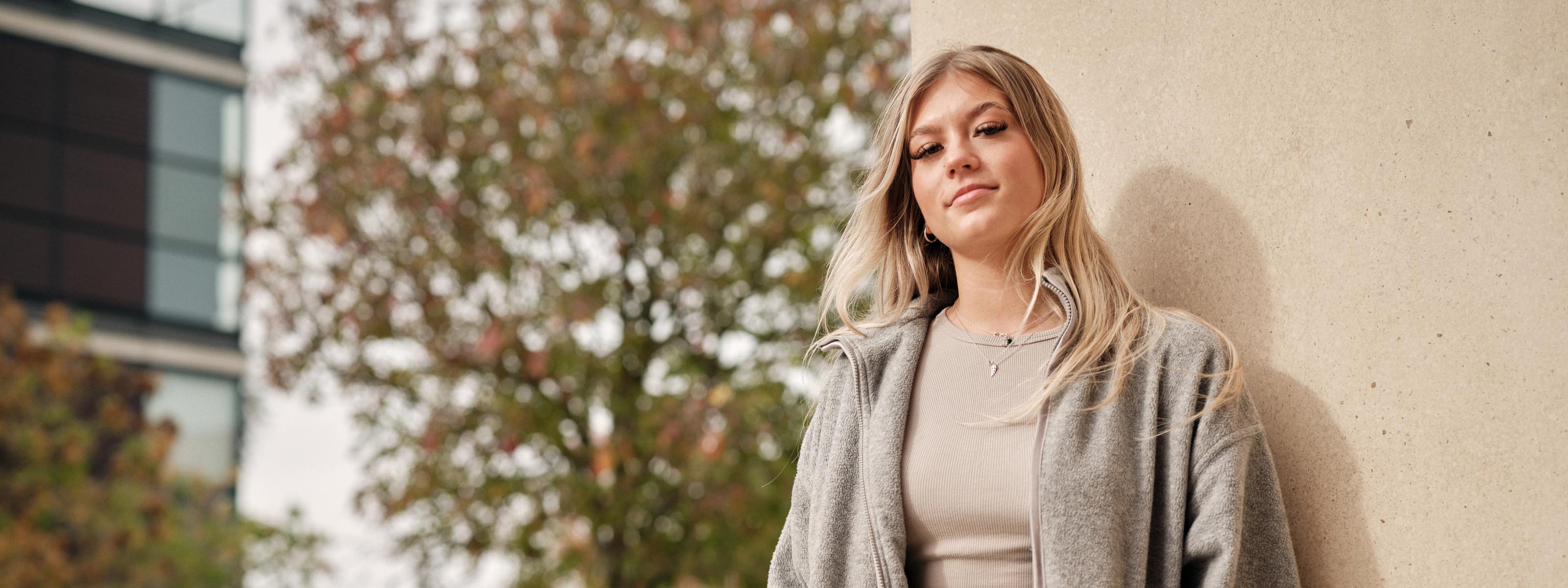 A student standing next to a wall on campus